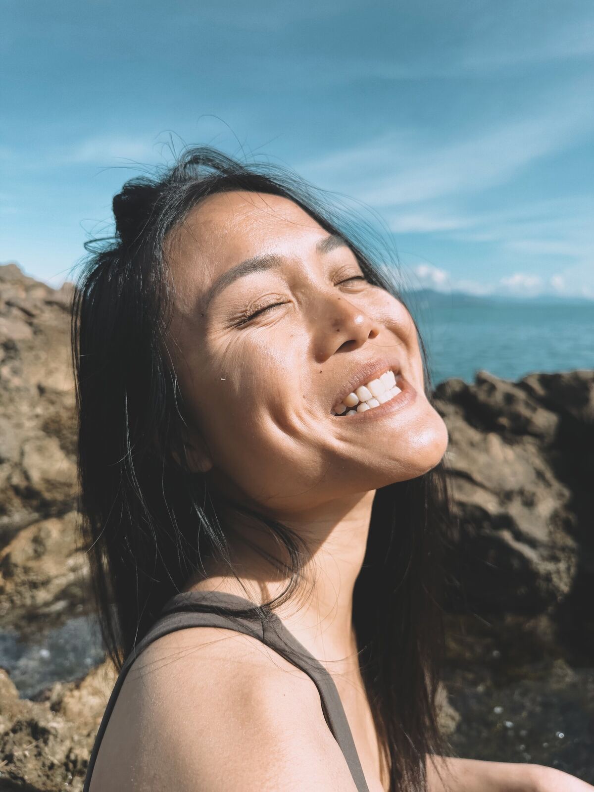Sophie Joe laughing in the sun by the sea